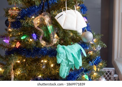 A Christmas tree displaying traditional ornaments, as well as personal protective equipment which has become commonplace due to the Coronavirus pandemic of 2020. - Shutterstock ID 1869971839