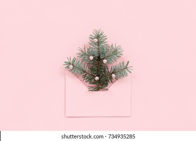 Christmas tree in envelope, minimal New Year`s card. Spruce branch with pearls on pink  background. Holidays, Congratulation concept