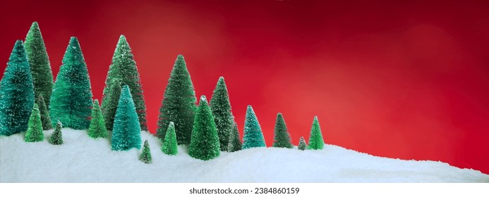 Christmas tree figurines forest in sparkling snow with bright red sky. Christmas background or wallpaper.