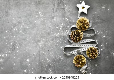 Christmas tree with fir cones from a measuring tape on a gray concrete background. Copy space. Flat lay. Creative composition. Holiday concept