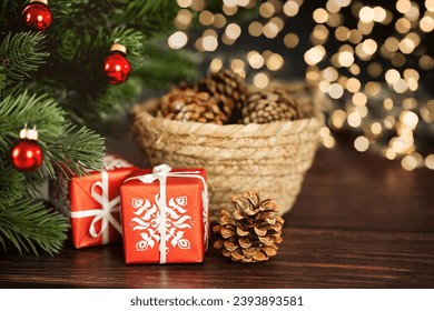 Christmas tree, gift boxes and pine cones inside a wicker basket on empty table with blurred bokeh lights - Powered by Shutterstock