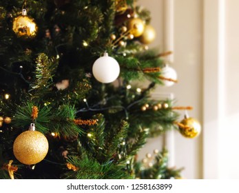 Christmas Tree With Golden And White Balls With Tiny Led Lights And White Wooden Panels As Background