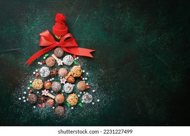 Christmas tree made of chocolate truffles, hazelnuts, anise stars, decorations, spoons and powdered sugar snow on dark green background. Christmas holiday card. Holiday food concept for magazine page. - Powered by Shutterstock