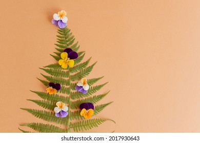 Christmas Tree Made Of Fern Leaves And Pansies On Beige Background With Copy Space. New Year Concept