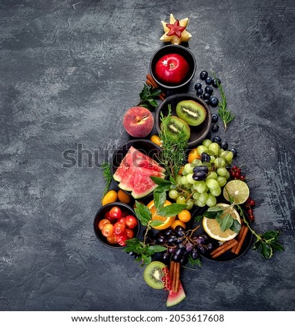 Christmas tree made of fruits on dark background. New Year Holidays concept. Top view, flat lay, copy space