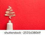 Christmas tree made of skin foundation and tube on red background, top view. Space for text