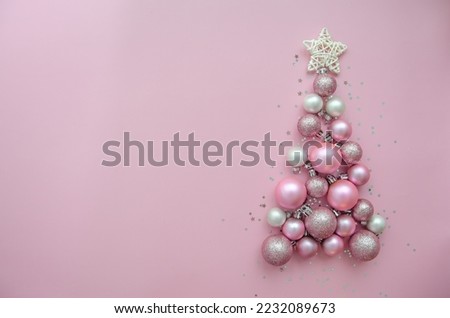 Christmas tree made of stars, confetti, pink balls on pink background. Flat lay, top view. Xmas greeting card with text - Merry Christmas.