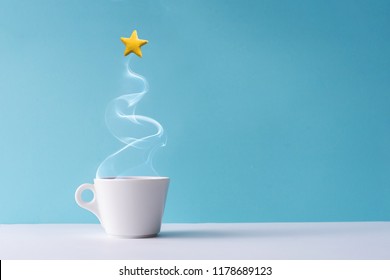 Christmas tree made of steaming coffee or hot drink with yellow star cookie. Winter holiday concept. Minimal New Year background.