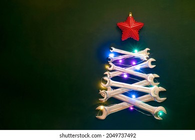 Christmas tree made of wrenches for car, star, string lights. Industrial greeting card. Copy space. Merry christmas and happy new year concept.