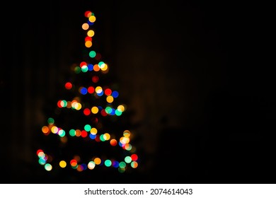 Christmas tree multicolored bokeh on dark background. Defocused multi colored lights. New Year, Christmas background, abstract texture. Copy space