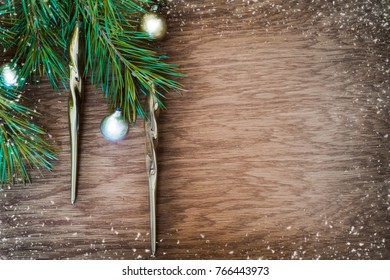 Christmas tree with old golden decoration icicle and silver glass ball on a wooden board (with snow)