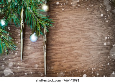 Christmas tree with old golden decoration icicle and silver glass ball on a wooden board (with snow bokeh)