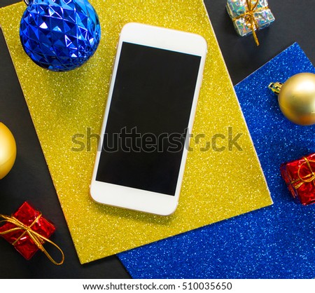 Christmas tree ornament and smartphone flat composition. White smartphone with black screen on table. Christmas or New Year mockup with personal gadget. Smartphone mock-up with winter holiday decor