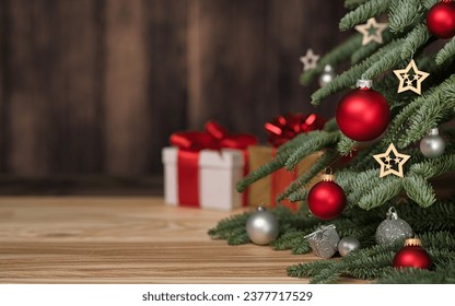 Christmas tree with ornaments, gift boxes and dark wooden wall as copy-space in the background