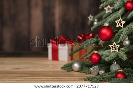 Christmas tree with ornaments, gift boxes and dark wooden wall as copy-space in the background