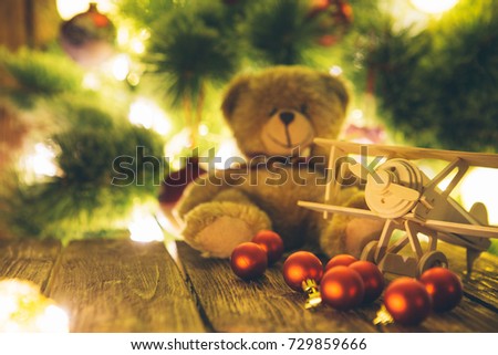 Christmas tree with presents and handmade wooden airplane toys on wooden table.