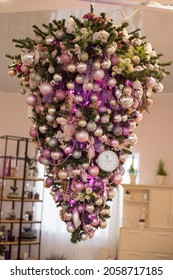 Christmas tree with purple balls hangs upside down from the ceiling. Unusual interior decoration