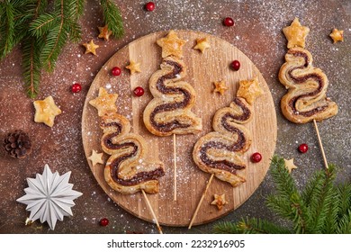 Christmas tree shape puff pastry cakes with chocolate filling and sugar powder. Delicious homemade New Year sweet baking. 