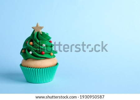 Christmas tree shaped cupcake on light blue background. Space for text