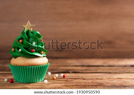 Christmas tree shaped cupcake on wooden table. Space for text