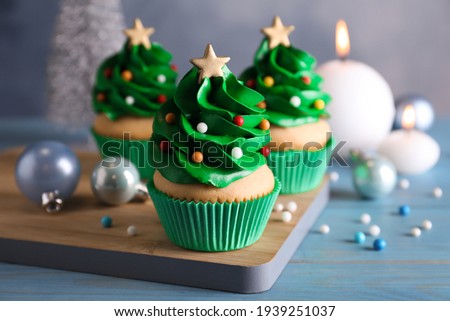 Christmas tree shaped cupcakes and decor on light blue wooden table