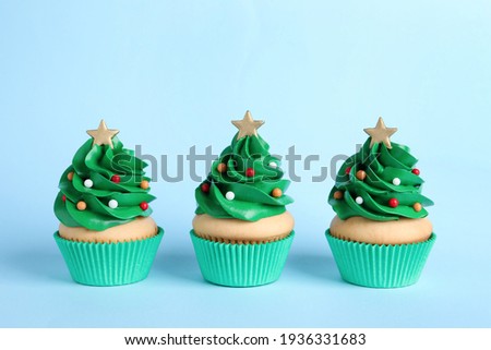 Christmas tree shaped cupcakes on light blue background