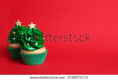 Christmas tree shaped cupcakes on red background. Space for text