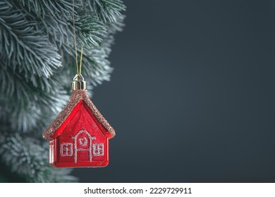 Christmas tree toy in the form of a red house on the Christmas tree with copy space, concept House insurance, house gift