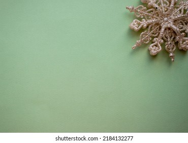 Christmas Tree Toy Golden Snowflake In The Corner On A Green Background. Christmas Card. Flat Lay, Top View, Copy Space