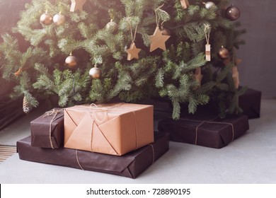 Christmas tree with wooden rustic decorations and presents under it in loft interior.