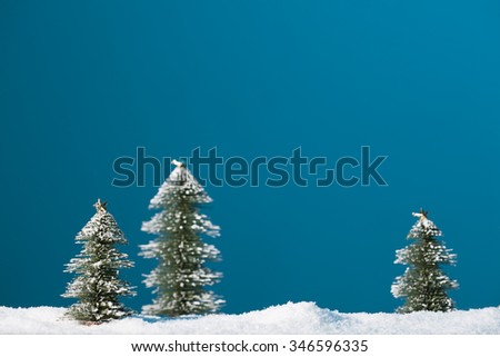 Christmas trees stand in the snow on a blue background.