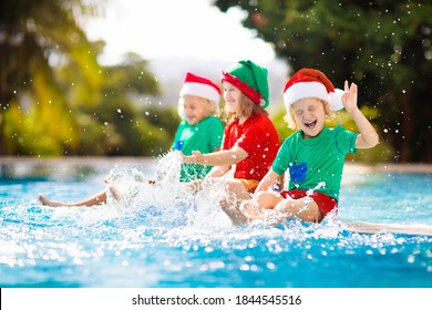 Christmas Vacation On Tropical Island. Kids In Santa Hat Playing In Swimming Pool On Family Xmas Vacation. Winter Holidays At The Beach. Travel With Children. Boy And Girl Swim. Merry Christmas Card.