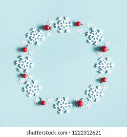 Christmas or winter composition. Wreath made of snowflakes and red berries on pastel blue background. Christmas, winter, new year concept. Flat lay, top view, copy space