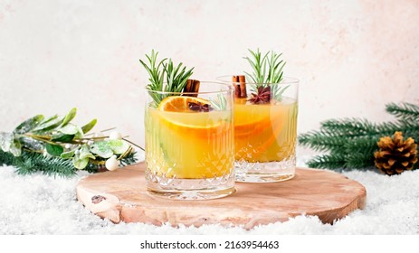 Christmas or winter warming bourbon old fashioned with oranges, cinnamon and rosemary on wooden table with tree branches and decor - Powered by Shutterstock