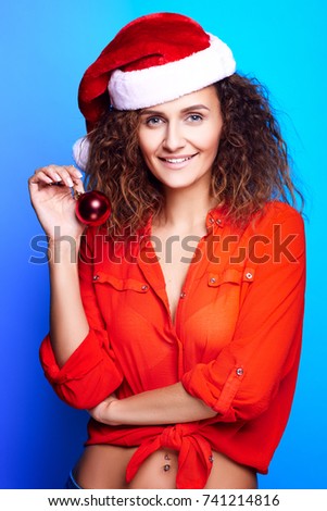 Christmas Woman holding decoration in Santa Ha and smilet. Funny Laughing Surprised Woman Portrait. Open Mouth. True Emotions.  Concept of christmas