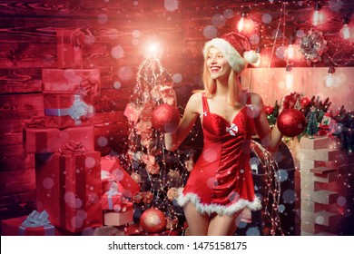 Christmas woman. Magic Christmas bokeh. Cute Christmas woman in red lingerie showing Christmas balls. Celebrating party
