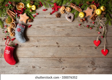 Christmas wooden background with fir branches, socks stockings for gifts, decoration with apples, cookies, cinnamon, nuts, red berries and hearts. Space for greeting text, top view.  - Powered by Shutterstock