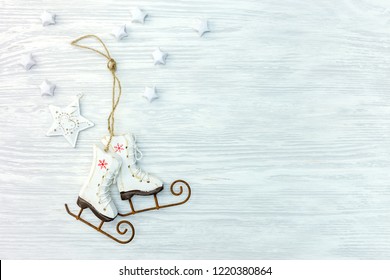 christmas wooden background with small ice skates and white stars. flat lay