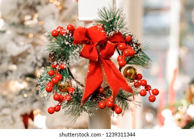 Christmas wreath decorated with red bow and artificial berries on the blurred background of white room - Powered by Shutterstock