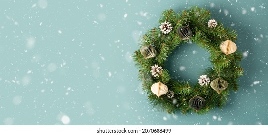 Christmas wreath with decoration on light blue green background and falling snow. Top view. Space for text - Powered by Shutterstock