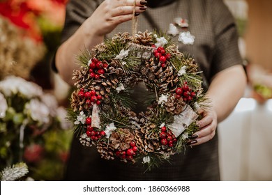 Christmas wreath decoration in red and brown classical style in the woman's hands. - Powered by Shutterstock