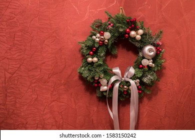 Christmas Wreath Handmade On A Red Wall Background. New Year's Interior Decoration