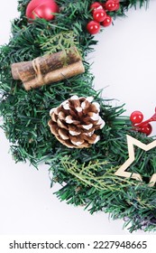 Christmas wreath isolated on white background. Decor elements are cones, glass balls, dried mugs of oranges, Christmas stars, cotton bolls. The basis of the wreath is spruce branches. - Shutterstock ID 2227948665