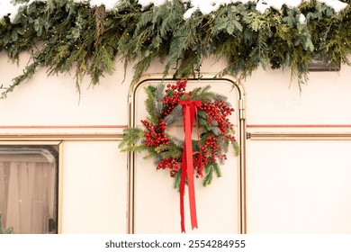 Christmas wreath made of holly berries and branch fir tied with a red bow hangs on door motor home. Festive Xmas wreath of fresh natural spruce branches. New Year. Traditional decor for Xmas holiday. - Powered by Shutterstock