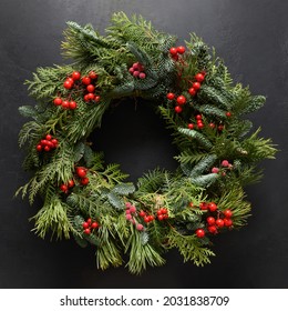 Christmas wreath of natural evergreen branches with red berries isolated on a black background. New Year. Traditional decoration for Xmas holiday. View from above. - Powered by Shutterstock