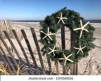 Christmas wreath on a beach fence with ocean in background.