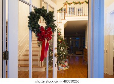 Christmas Wreath On A Glass Front Door Open To The Foyer With A Decorated Tree