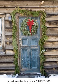 Christmas Wreath On A Rustic Door Of A Log Cabin