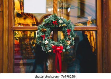 Christmas Wreath On The Store Glass Wooden Door. Christmas Or New Year Decoration. Winter Holidays Abstract Background. Decorative Detail In Christmas Market In Cesky Krumlov, Czech Republic, Europe.