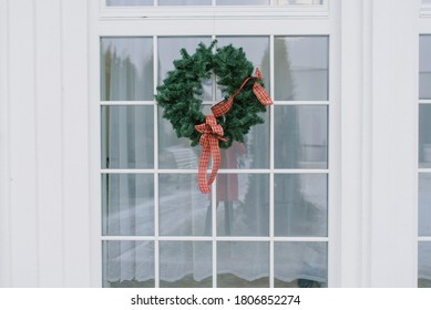 Christmas Wreath With A Red Bow On A White Window In A Private House